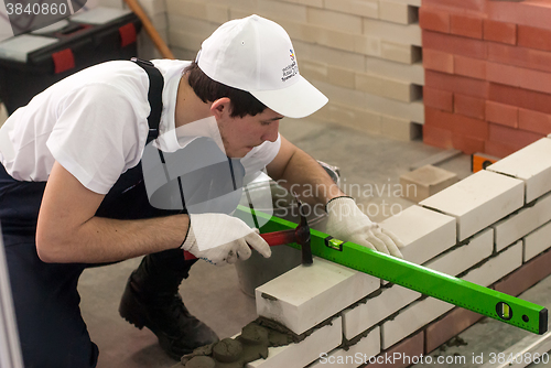 Image of Young bricklayer performs a task of competition