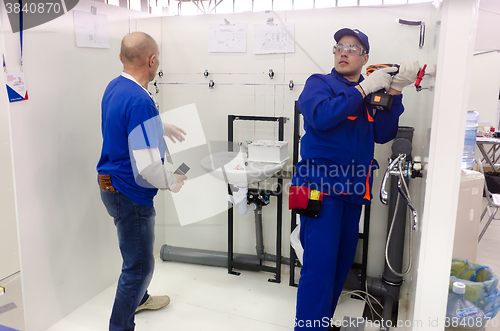 Image of Young plumber installs equipment for bathroom