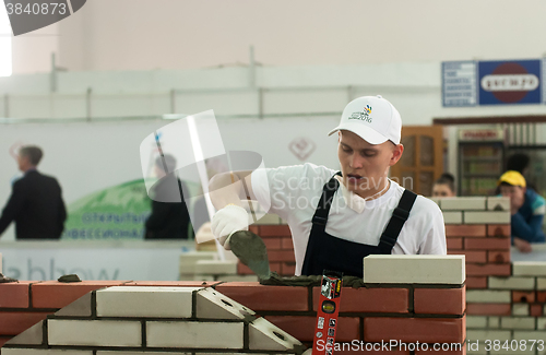 Image of Young bricklayer performs a task of competition