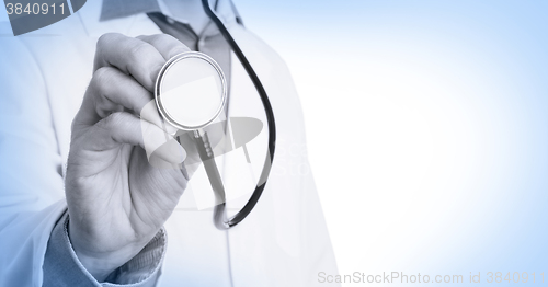 Image of Close up of a Doctor\'s hand, holding a stethoscope, medical blue