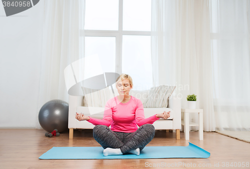 Image of happy woman stretching leg on mat at home