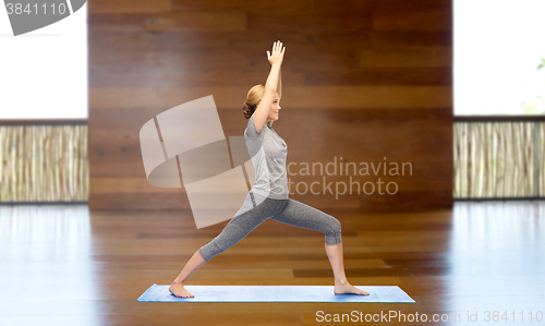 Image of woman making yoga warrior pose on mat