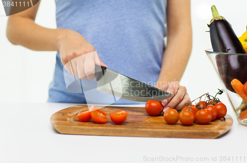 Image of close up of woman chopping tomatoes with knife