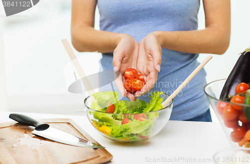 Image of close up of woman cooking vegetable salad at home