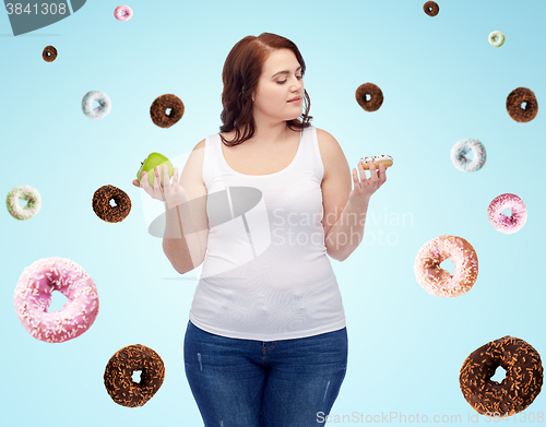 Image of young plus size woman choosing apple or cookie