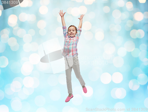 Image of happy little girl jumping in air over blue lights