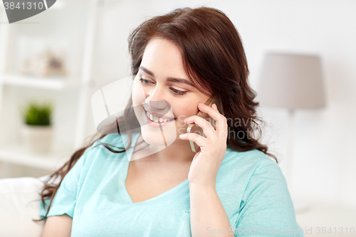 Image of plus size woman calling on smartphone at home