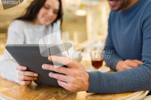 Image of happy couple with tablet pc drinking tea at cafe
