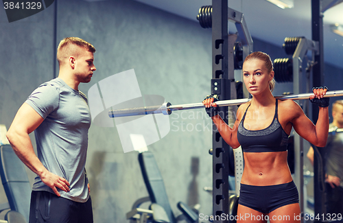 Image of man and woman with barbell flexing muscles in gym