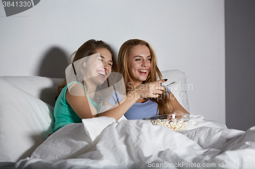 Image of happy friends with popcorn and watching tv at home