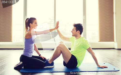 Image of man with personal trainer doing sit ups in gym