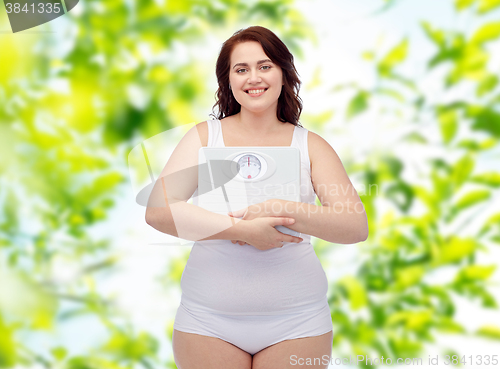 Image of happy young plus size woman holding scales