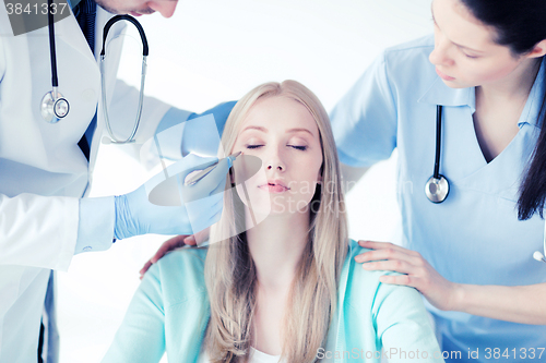 Image of plastic surgeon and nurse with patient