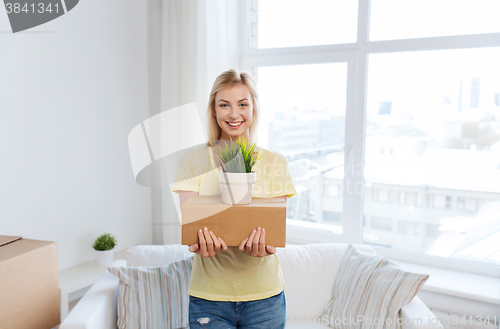 Image of smiling young woman with cardboard box at home