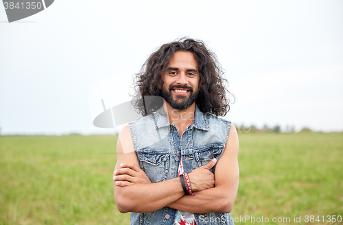 Image of smiling young hippie man on green field
