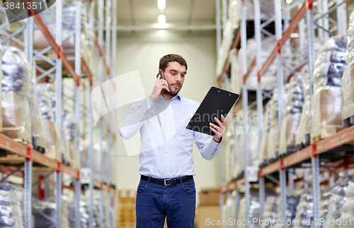 Image of man with clipboard and smartphone at warehouse