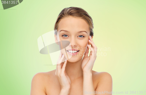 Image of smiling young woman touching her face