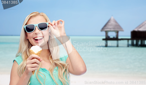 Image of happy woman in sunglasses with ice cream on beach
