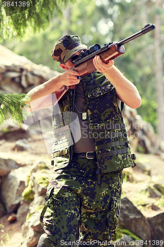 Image of soldier or hunter shooting with gun in forest