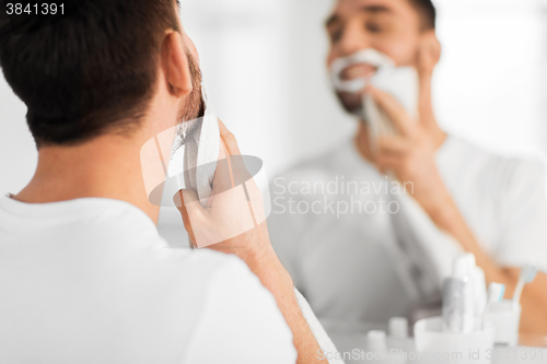 Image of close up of man removing shaving foam from face