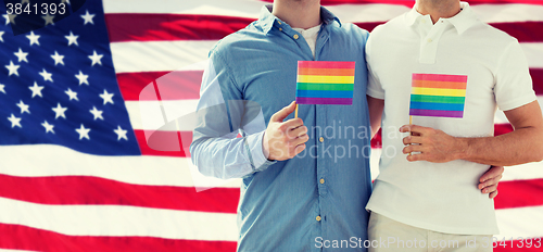 Image of close up of male gay couple holding rainbow flags