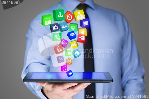 Image of Businessman holding a tablet pc with mobile applications icons on virtual screen . Internet and business concept.