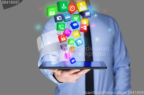 Image of Businessman holding a tablet pc with mobile applications icons on virtual screen . Internet and business concept.