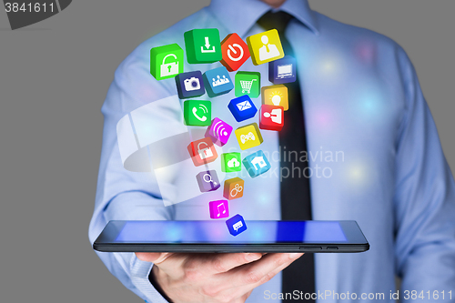 Image of Businessman holding a tablet pc with mobile applications icons on virtual screen . Internet and business concept.