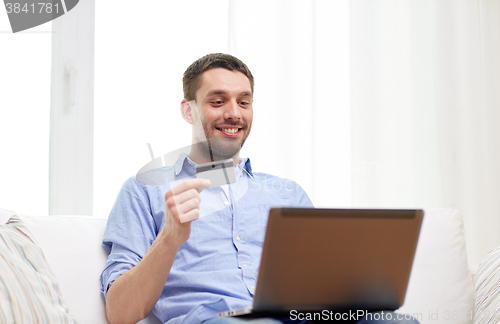 Image of smiling man with laptop and credit card at home