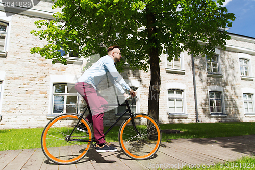 Image of happy young hipster man riding fixed gear bike