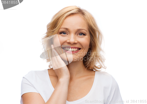 Image of smiling woman in white t-shirt touching her face