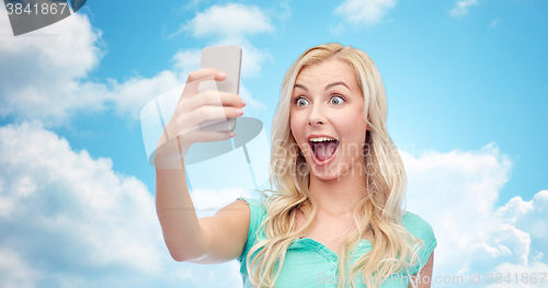 Image of smiling young woman taking selfie with smartphone