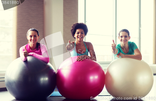 Image of group of smiling women with exercise balls in gym