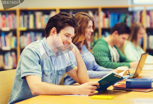 Image of happy student boy reading books in library