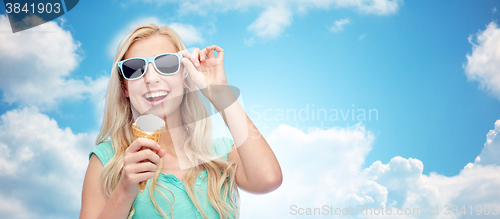 Image of happy young woman in sunglasses eating ice cream