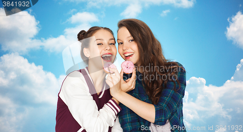 Image of happy pretty teenage girls eating donuts