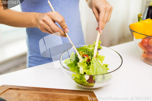 Image of close up of woman cooking vegetable salad at home