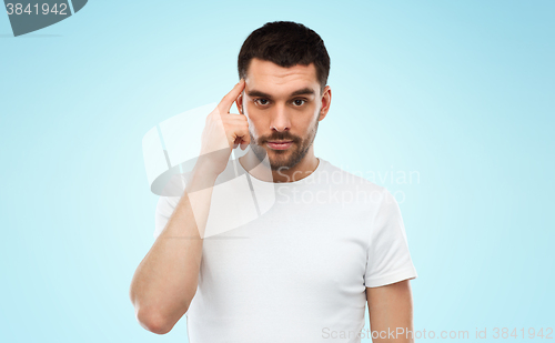 Image of man with finger at temple over blue background