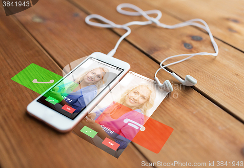 Image of close up of smartphone and earphones on wood