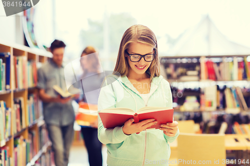 Image of happy student girl or woman with book in library