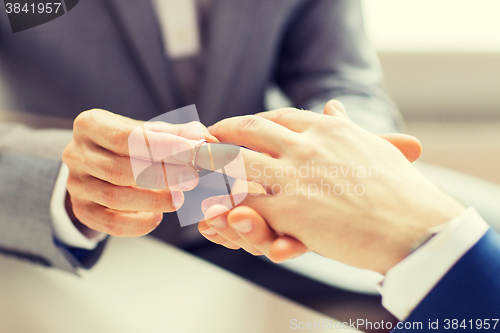 Image of close up of male gay couple hands and wedding ring