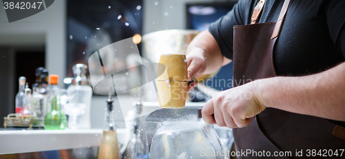 Image of Bartender breaks ice with wooden hammer