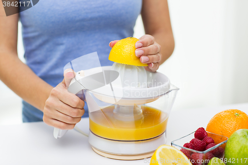 Image of close up of woman squeezing fruit juice at home
