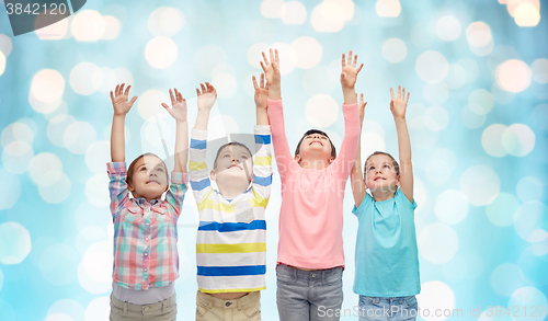 Image of happy children with raised hands over blue lights