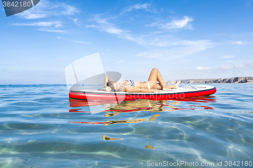 Image of Woman relaxing over a paddle surfboard