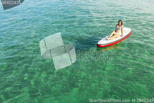 Image of Woman relaxing over a paddle surfboard