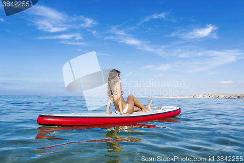 Image of Woman sitting over a paddle surfboard