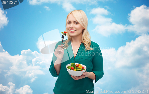 Image of smiling young woman eating vegetable salad