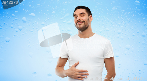Image of happy full man touching tummy over blue background