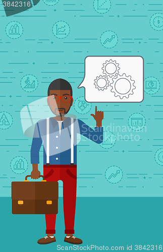 Image of Businessman pointing at cogwheels.